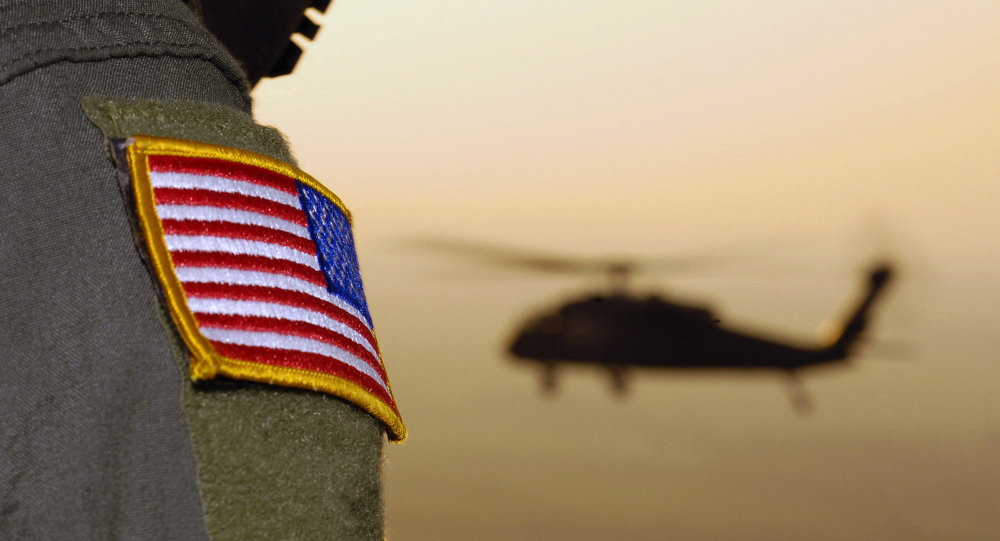 Lencana bendera Amerika pada seragam tentara, dengan helikopter di belakangnya.
