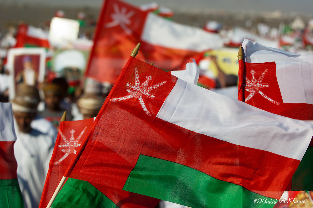 Bendera Oman dikibarkan di tengah kerumunan.