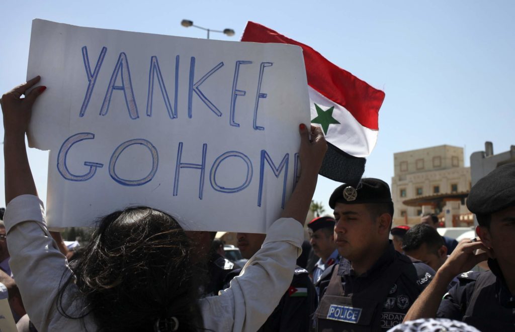 Demonstran membawa bendera Suriah dan tulisan Yankee Go Home.