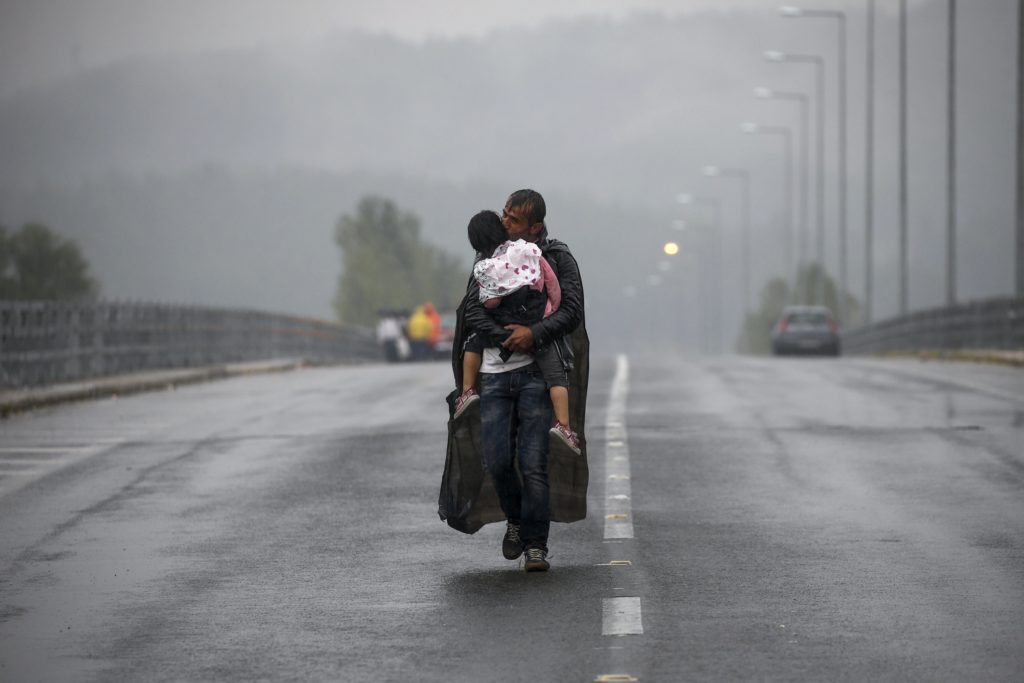 Pria menggendong anak sambil berjalan melewati jalan berasap.