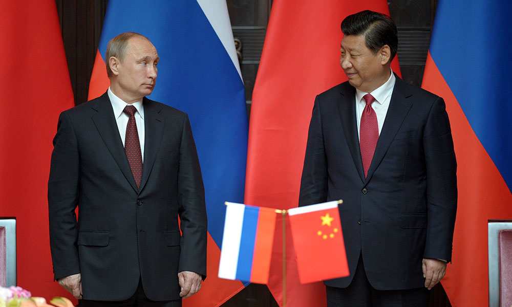 Vladimir Putin dan Xi Jinping berdiri bersama bendera Rusia dan Tiongkok.