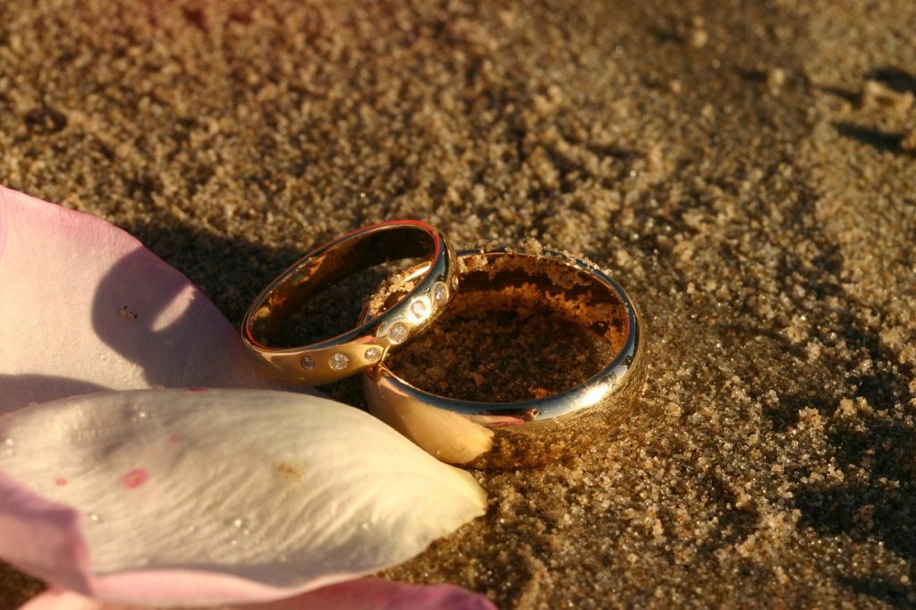 Dua cincin emas terletak di atas pasir.