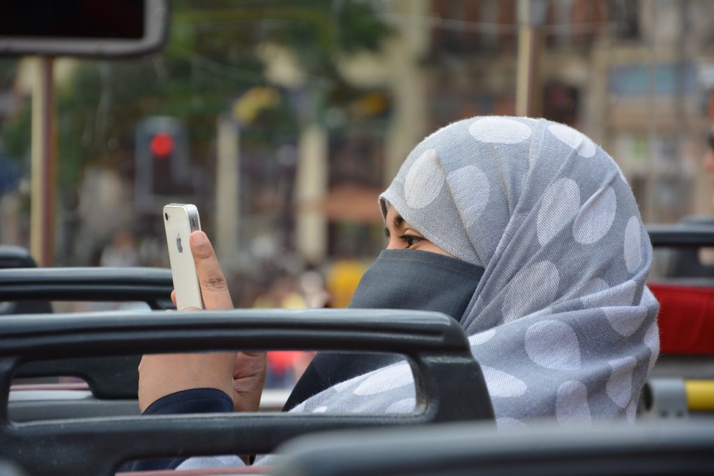 Perempuan berjilbab duduk di kendaraan umum.