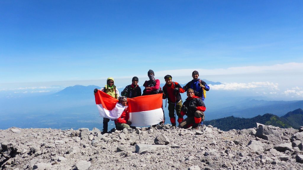 Pendaki membawa bendera Indonesia di puncak gunung.