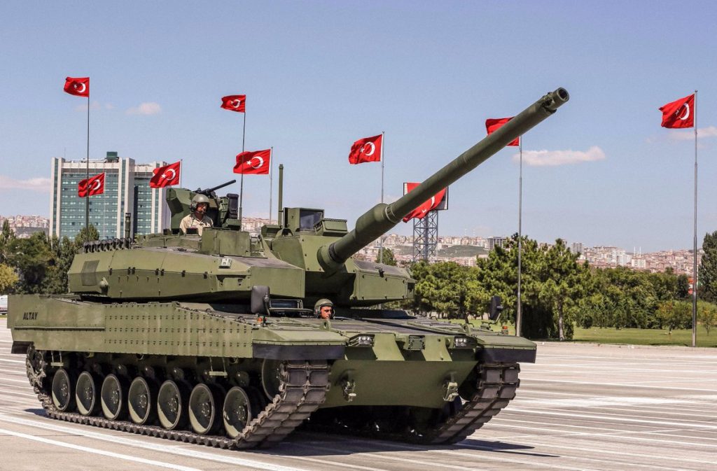 Tank melintas di dekat bendera-bendera Turki.