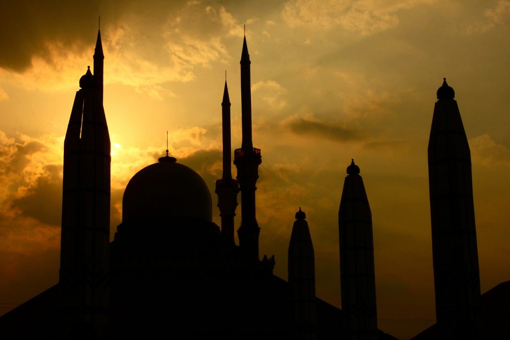 Siluet masjid dan menara saat matahari terbenam.