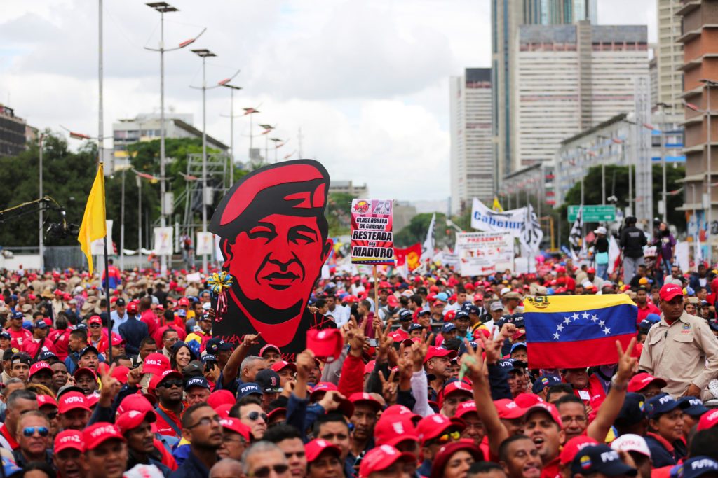 Kerumunan berpakaian merah membawa poster besar Hugo Chavez.