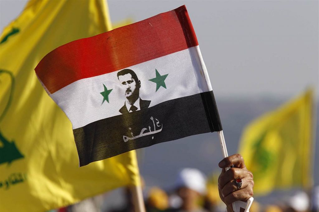 Bendera Suriah dengan potret Bashar al-Assad dikibarkan.