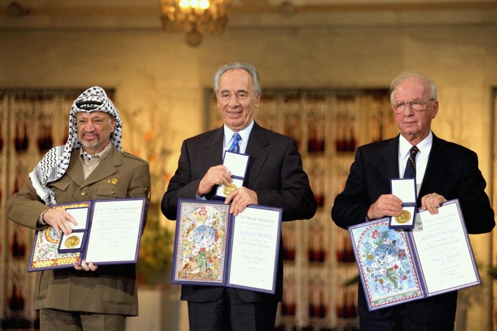 Yasser Arafat, Shimon Peres, dan Yitzhak Rabin memegang sertifikat penghargaan.