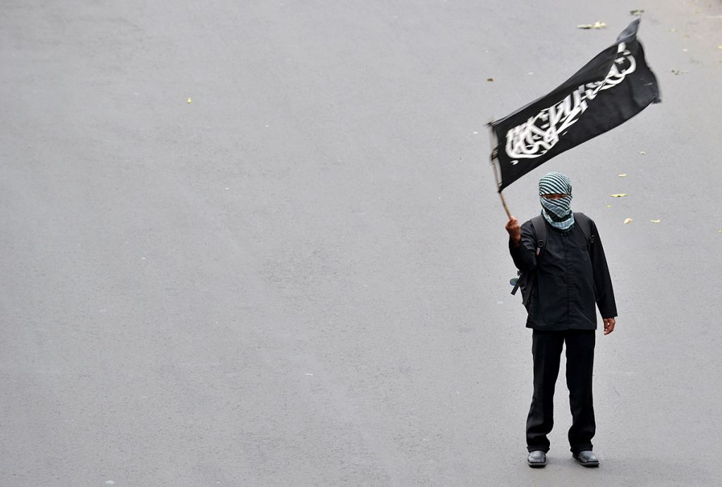 Sosok pria memegang bendera hitam bertuliskan Arab.