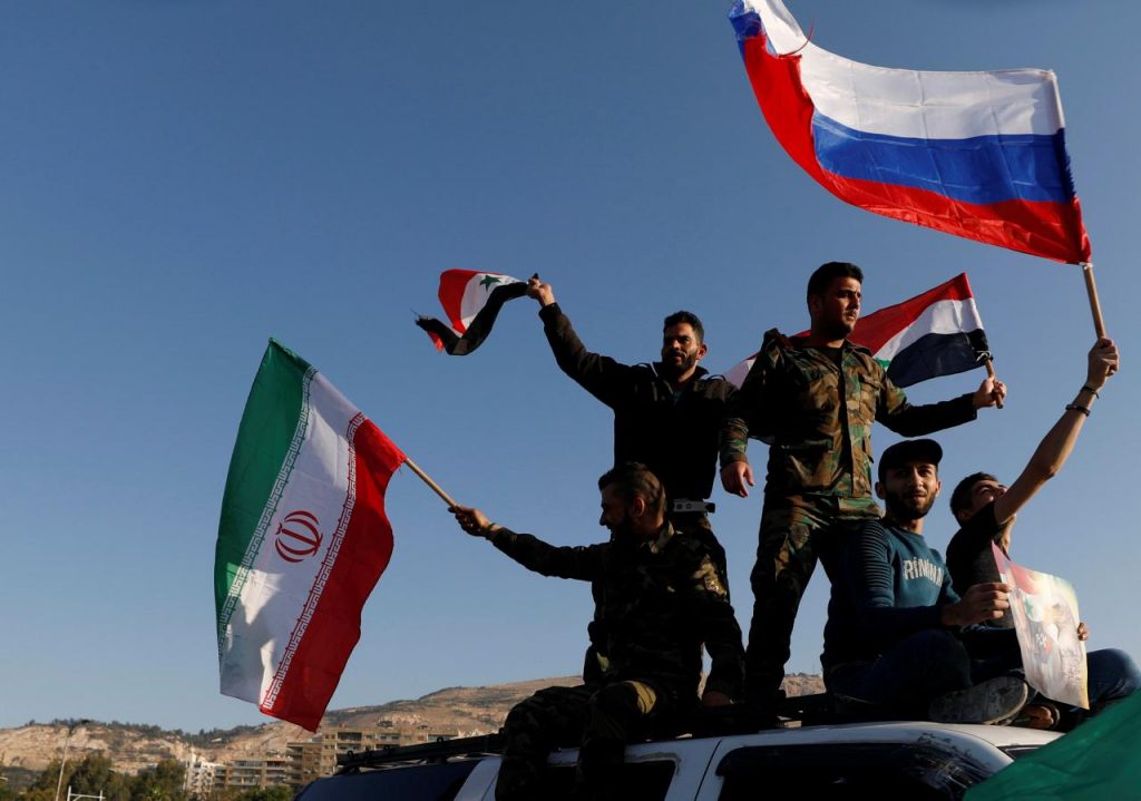 Peserta aksi mengibarkan bendera Iran, Rusia, dan Suriah dari atas mobil.