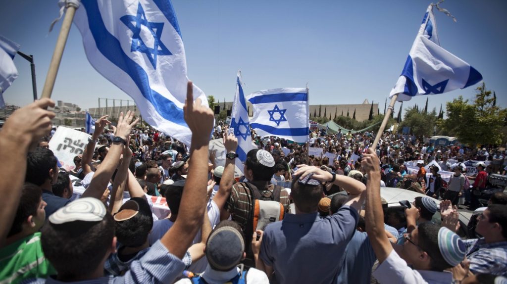 Kerumunan peserta aksi mengibarkan bendera Israel.